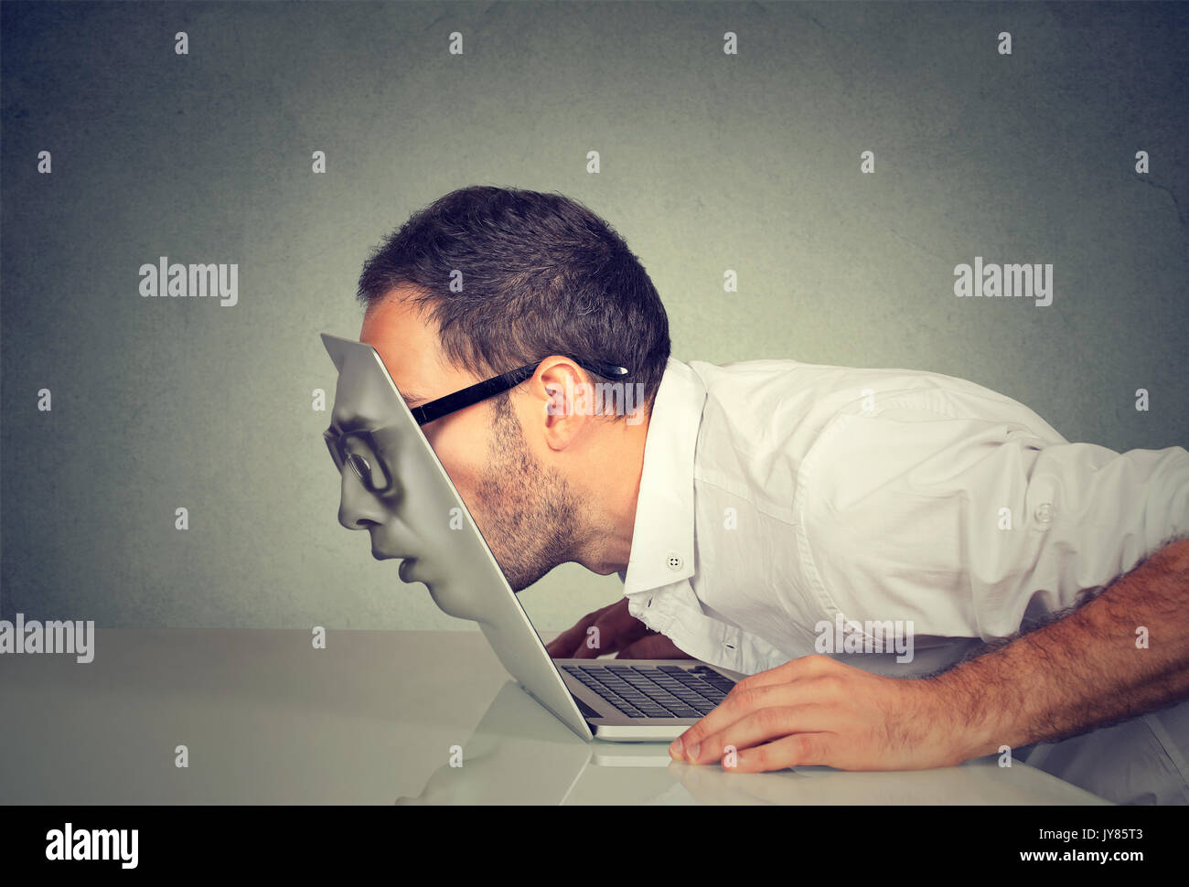 Giovane uomo d affari in bicchieri passando la sua testa attraverso un schermo di computer portatile Foto Stock
