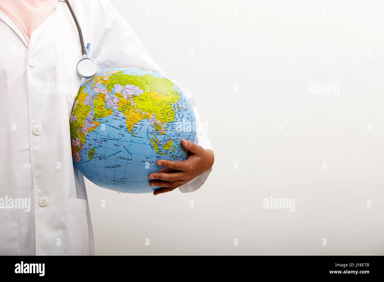 Il malese medico donna holding globe sullo sfondo bianco Foto Stock