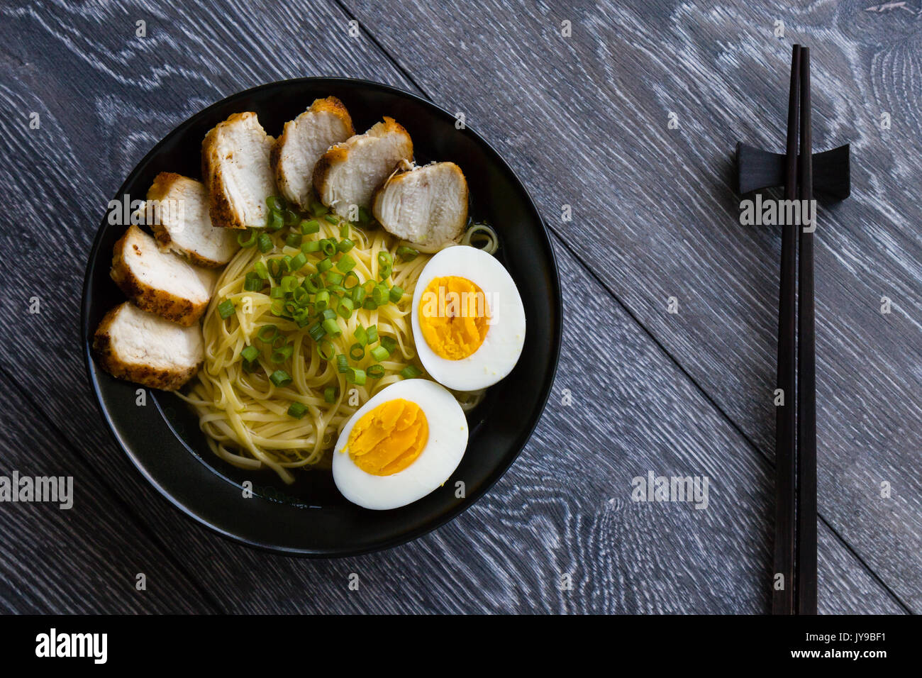 Giapponese ramen zuppa di pollo e uova sode o nel vaso nero Foto Stock