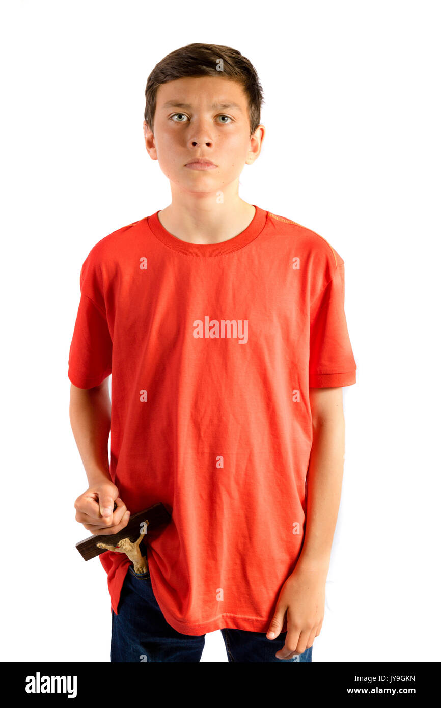 Giovane ragazzo adolescente isolata contro bianco rimuovendo un cruxifix da tasca Foto Stock
