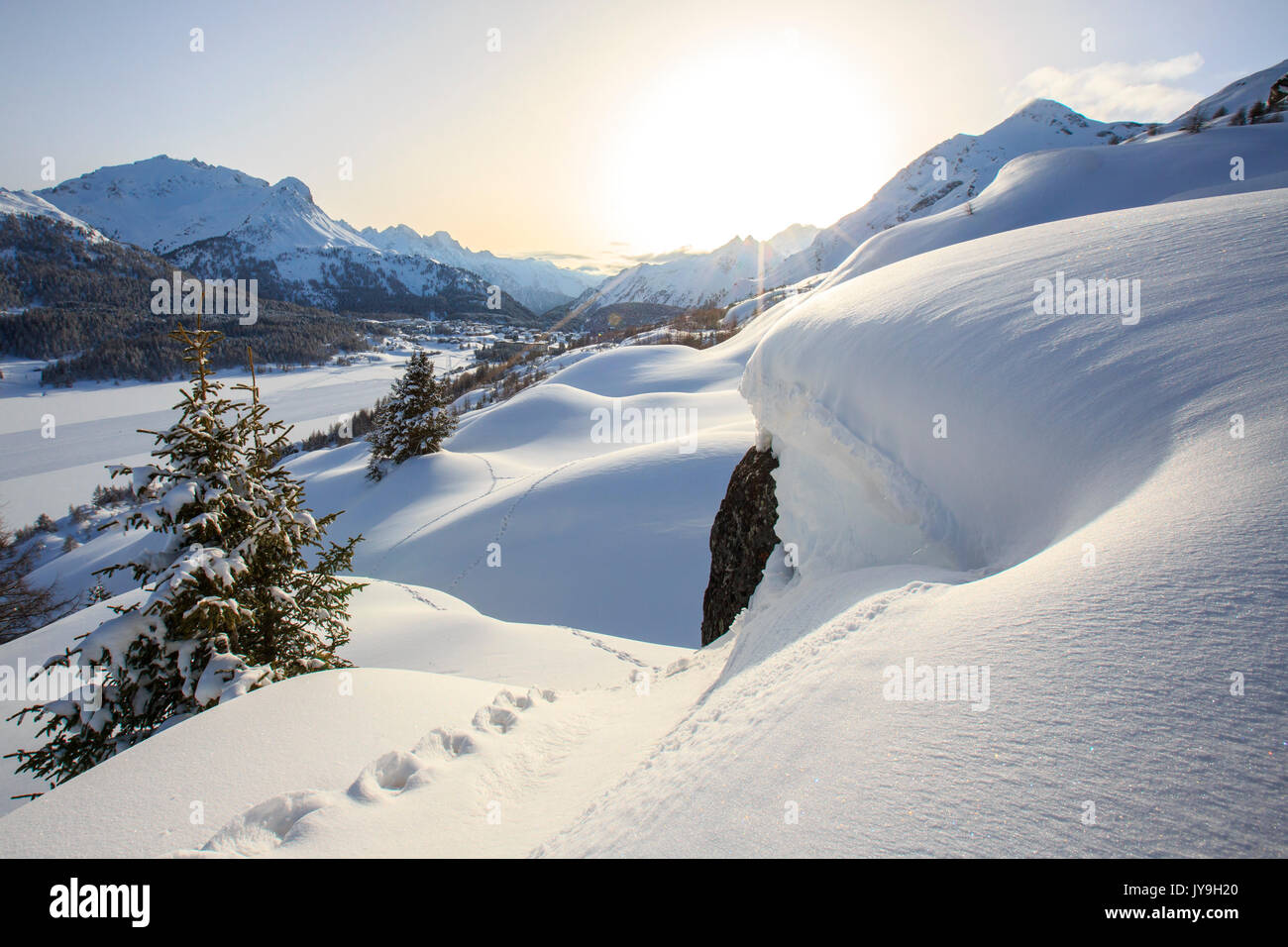 Un sole velato da nebbie si illumina le orme lasciate da snowshoers presso il Passo del Maloja e il cantone dei Grigioni. Engadina. svizzera. l'Europa Foto Stock