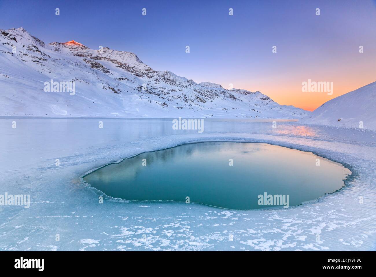Colori tenui di una fredda alba riflessa in una piscina di acqua turchese circondato da neve nel mezzo del lago bianco. Passo Bernina. Cantone di graubuen Foto Stock
