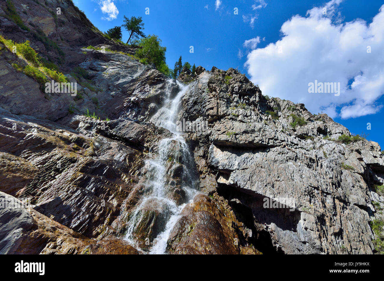 Estate paesaggio di montagna della cascata Shirlak nelle rocce delle montagne di Altai a bright giornata soleggiata con nuvole bianche su un cielo blu, Repubblica degli Altai, Siberi Foto Stock