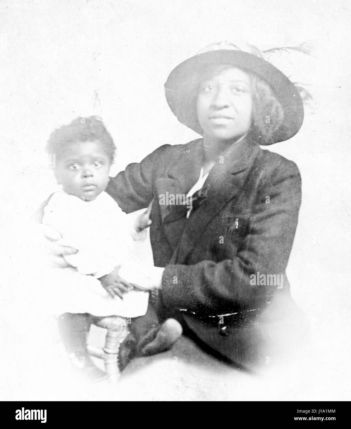 Madre afroamericana che indossa un cappello e tiene in braccio sua figlia, che ha un'espressione facciale sorpresa, 1944. Foto Stock