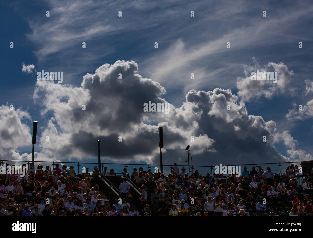 Gli spettatori seduti courtside a campionati di Wimbledon 2017, nuvole scure si raccolgono sul terreno, Londra, Gran Bretagna, Regno Unito. Foto Stock