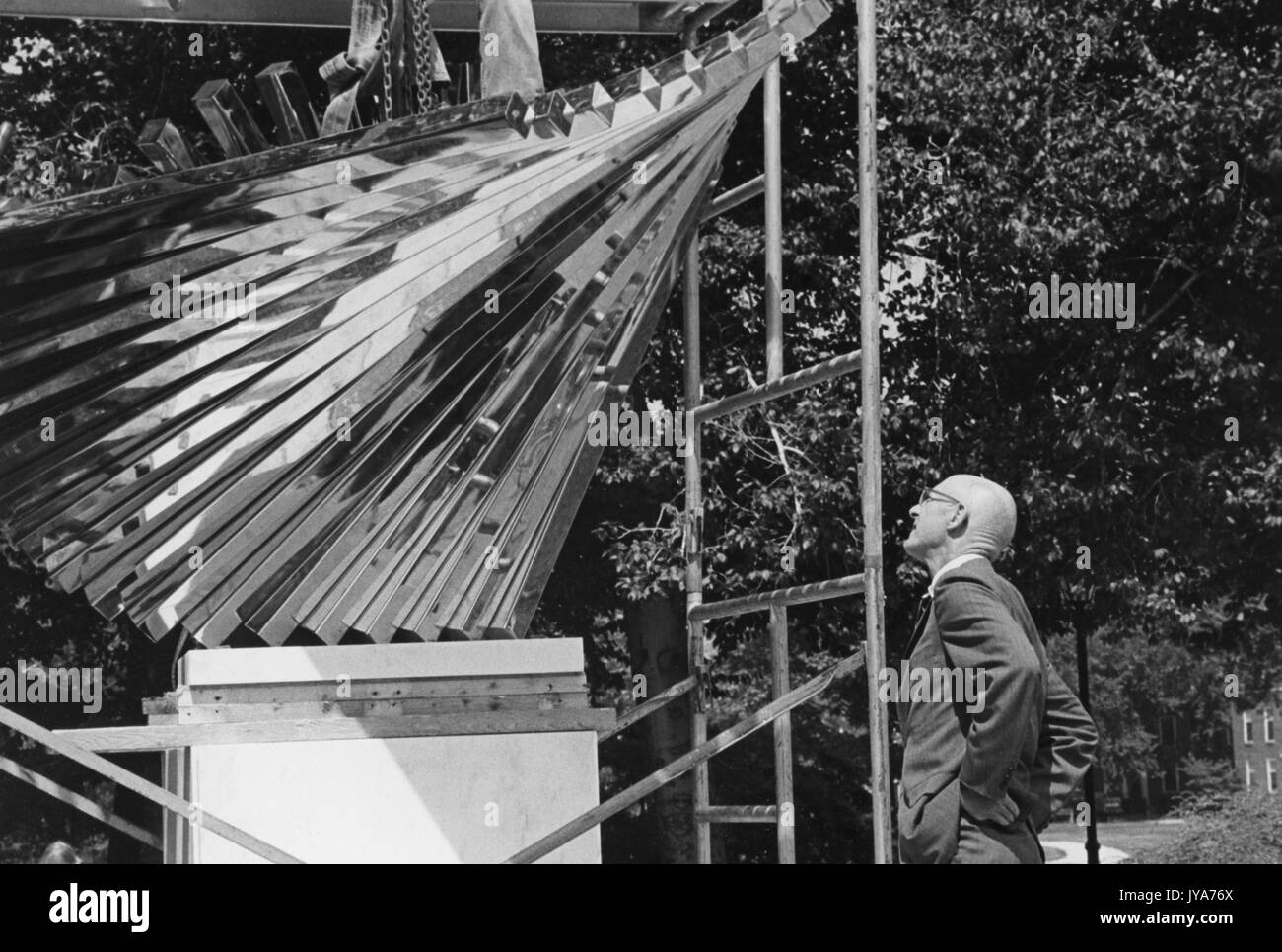 Un onlooker esamina la scultura centenaria, creata dallo scultore David Brown per celebrare il centesimo anniversario della fondazione della Johns Hopkins University, che sarà rivelata nel campus di Homewood dell'Università di Baltimora, Maryland. 1976. Foto Stock