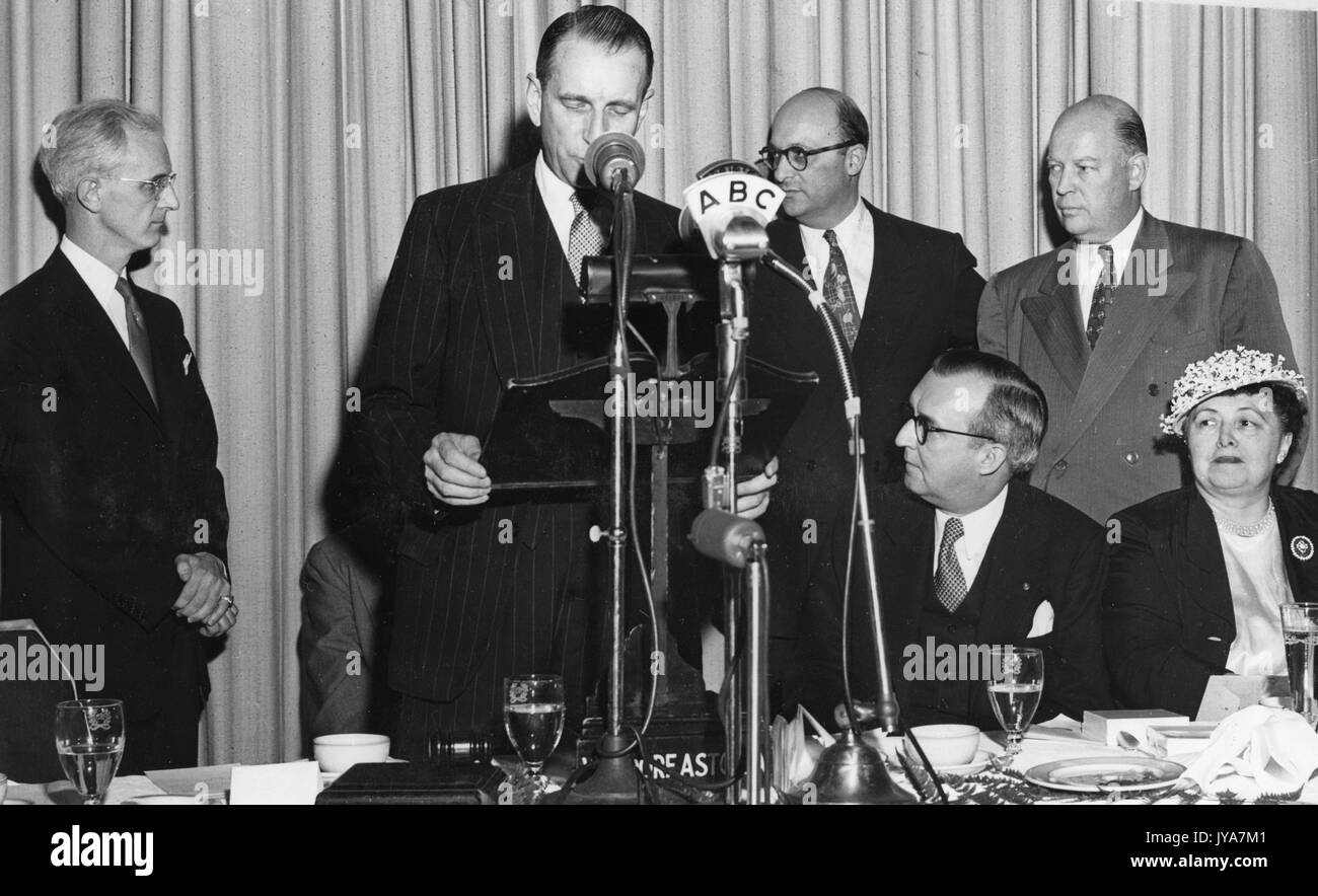 La televisione americana Lynn host poole si alza e si affaccia su mentre edward settimane, magazine editor, legge una citazione per la televisione mostra la Johns Hopkins science review, altri ospiti seduti e guardando, 1953. Foto Stock