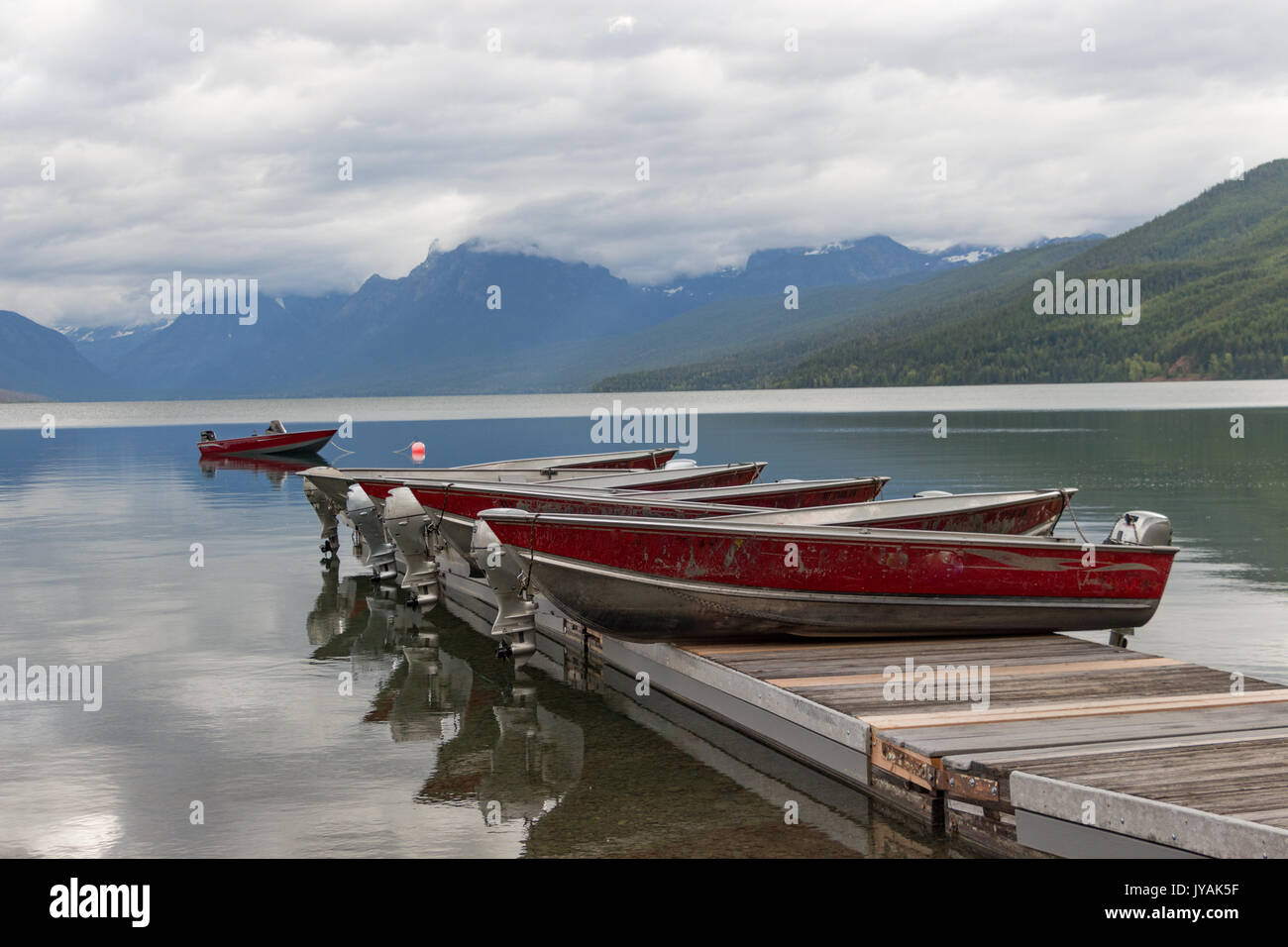 Categoria : Barche sul molo con mountain-gamma background e simili a specchio Lago McDonald con riflessioni di Cloud Foto Stock