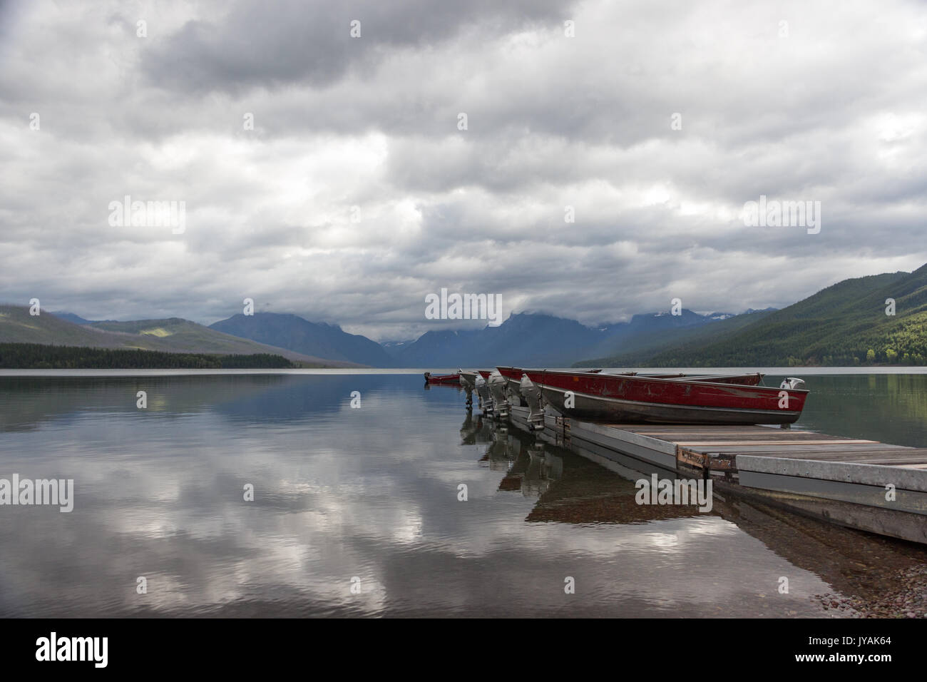 Categoria : Barche sul molo con mountain-gamma background e simili a specchio Lago McDonald con riflessioni di Cloud Foto Stock