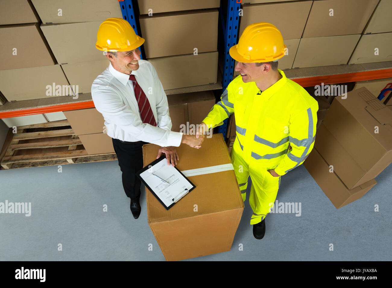 Sorridente Warehouse Manager e lavoratore stringono le mani in magazzino Foto Stock