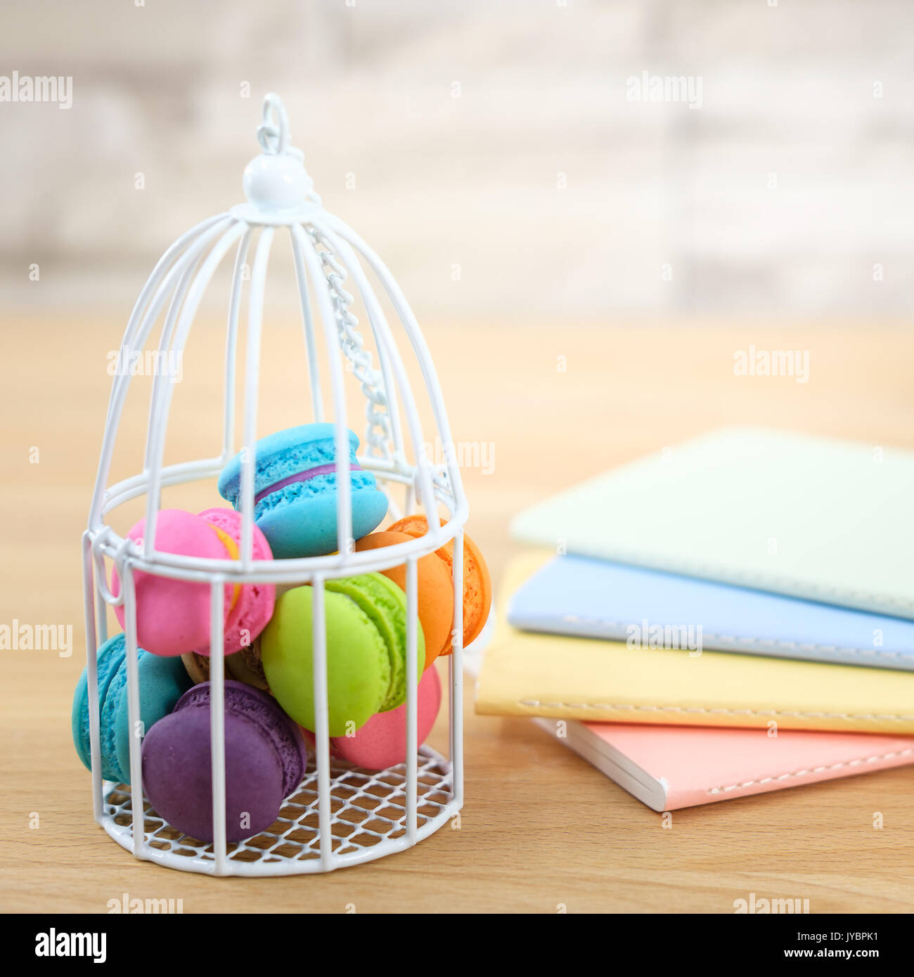 Dolce e colorata amaretto cookies nella gabbia per uccelli con molti graziosi del notebook su sfondo di legno con uno spazio vuoto,fuoco selettivo, Dessert. Foto Stock
