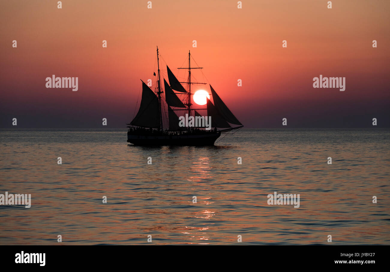 Un veliero nel Mare Egeo mentre il sole tramonta Santorini Cyclades Grecia Europa Foto Stock