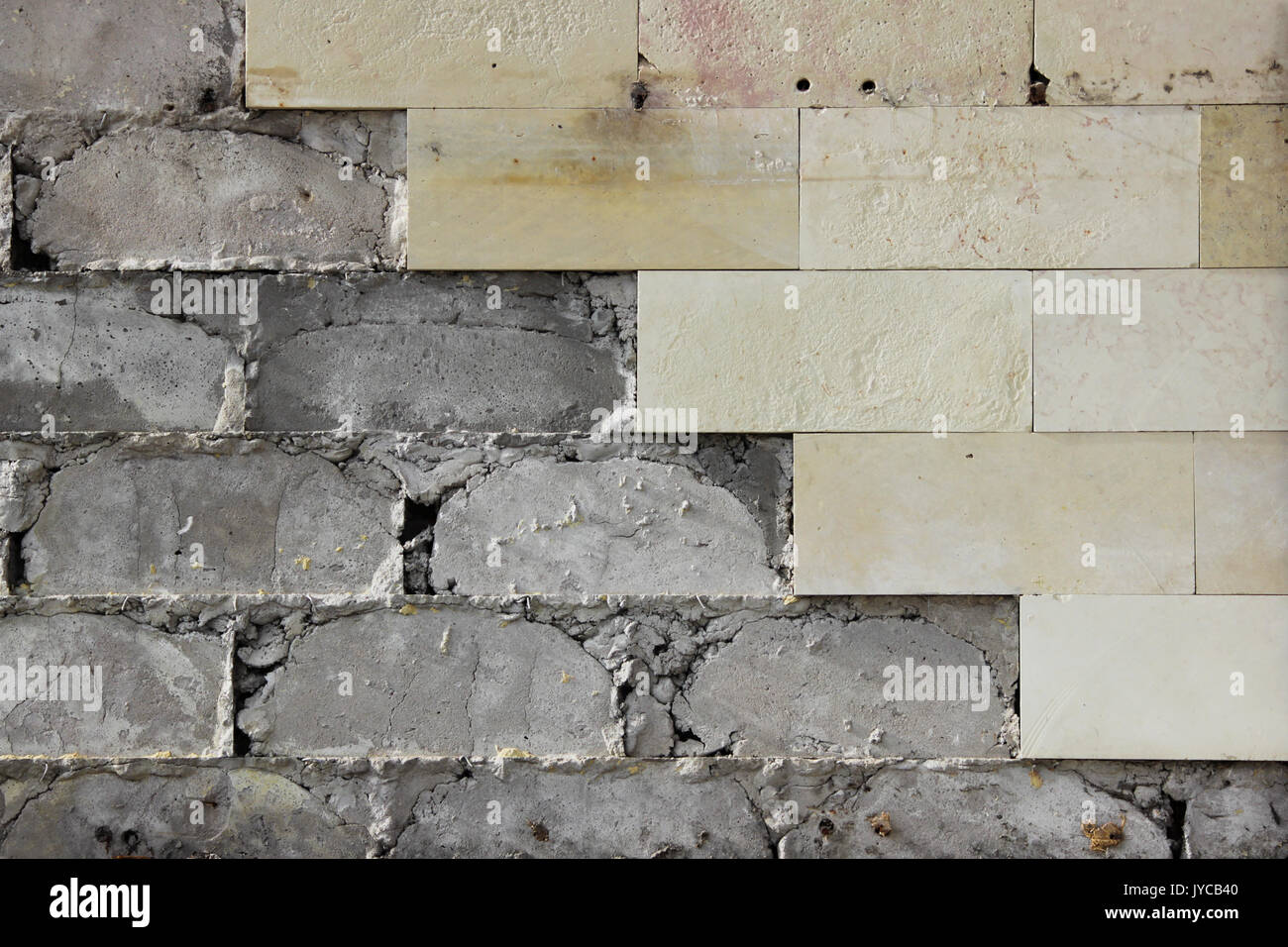 Grande Muro beige piastrelle è caduto, la consistenza del calcestruzzo di fondazione. Di lavoro difettoso. Foto Stock