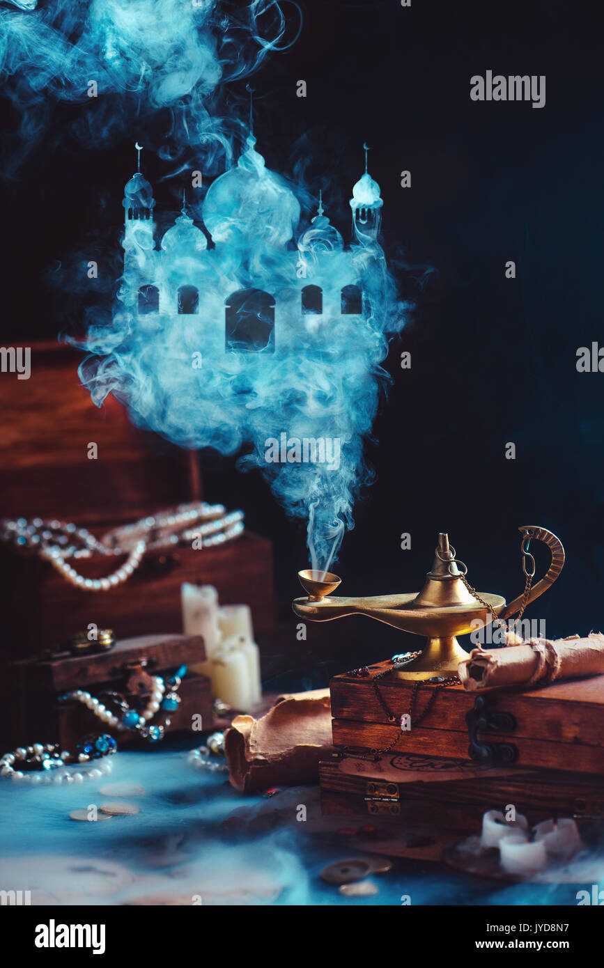 Dark dreamy ancora in vita con la lampada magica e mistica la formazione di fumo di un castello arabo. scatole piene di tesori e gioielli su uno sfondo. Foto Stock
