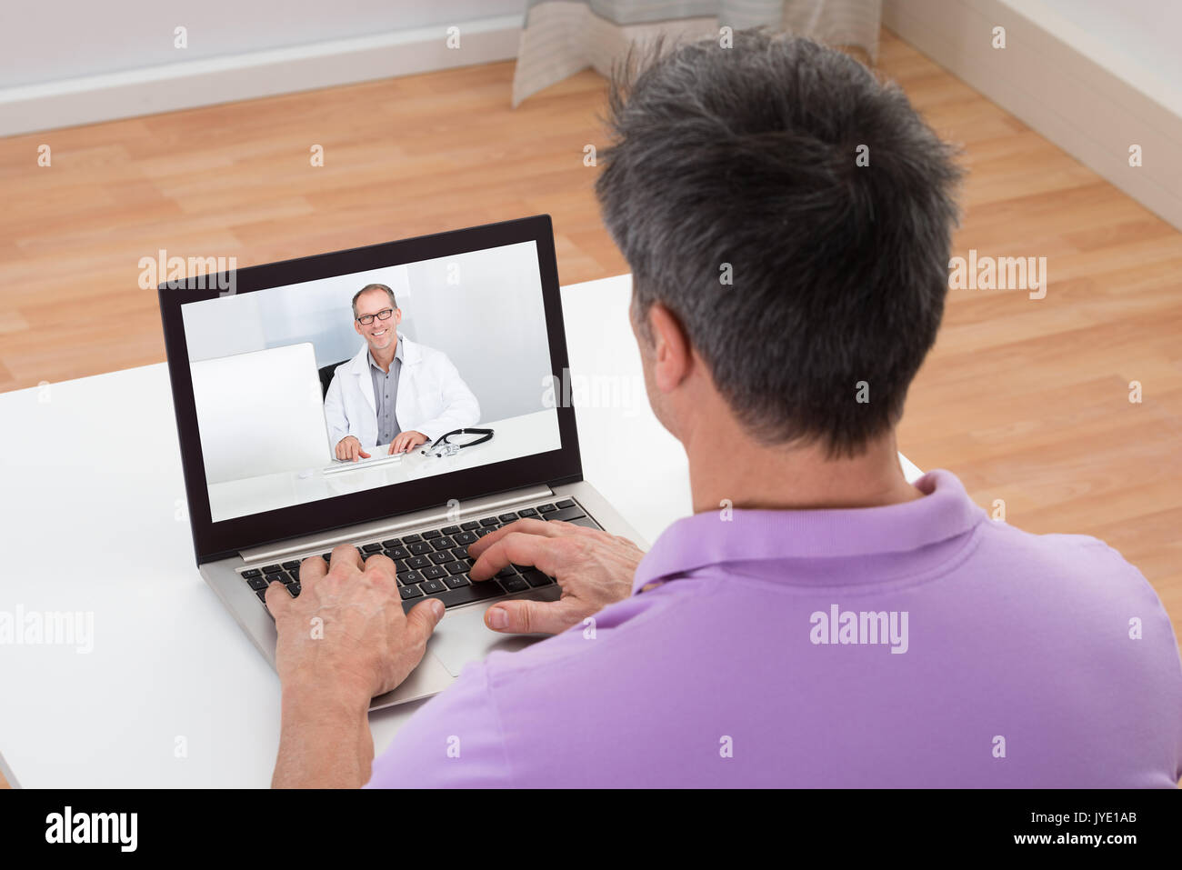 L'uomo avente la Video Chat con medico sul portatile a casa Foto Stock