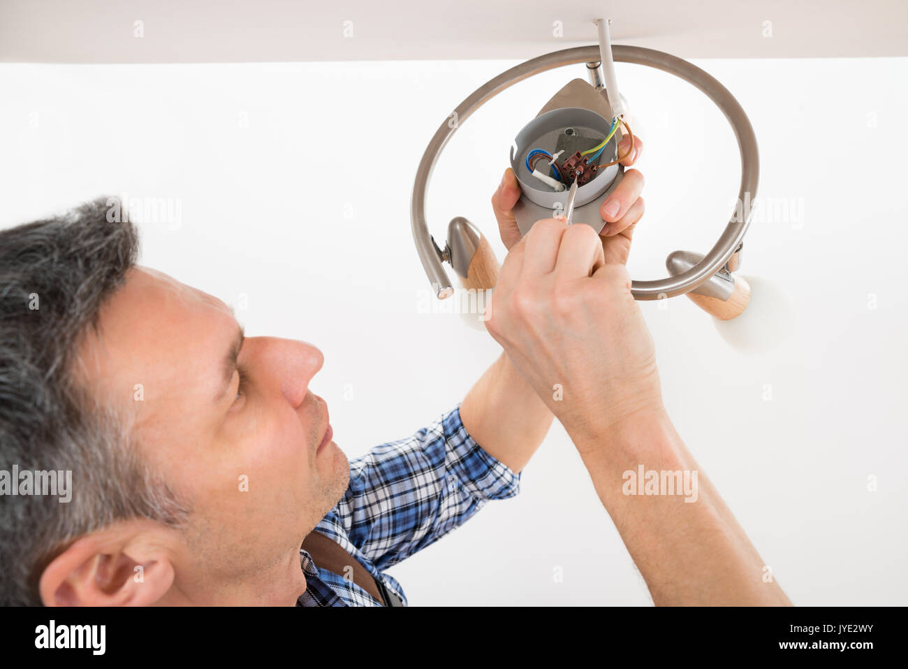 Close-up di un elettricista maschio che fissa la luce sul soffitto Foto Stock