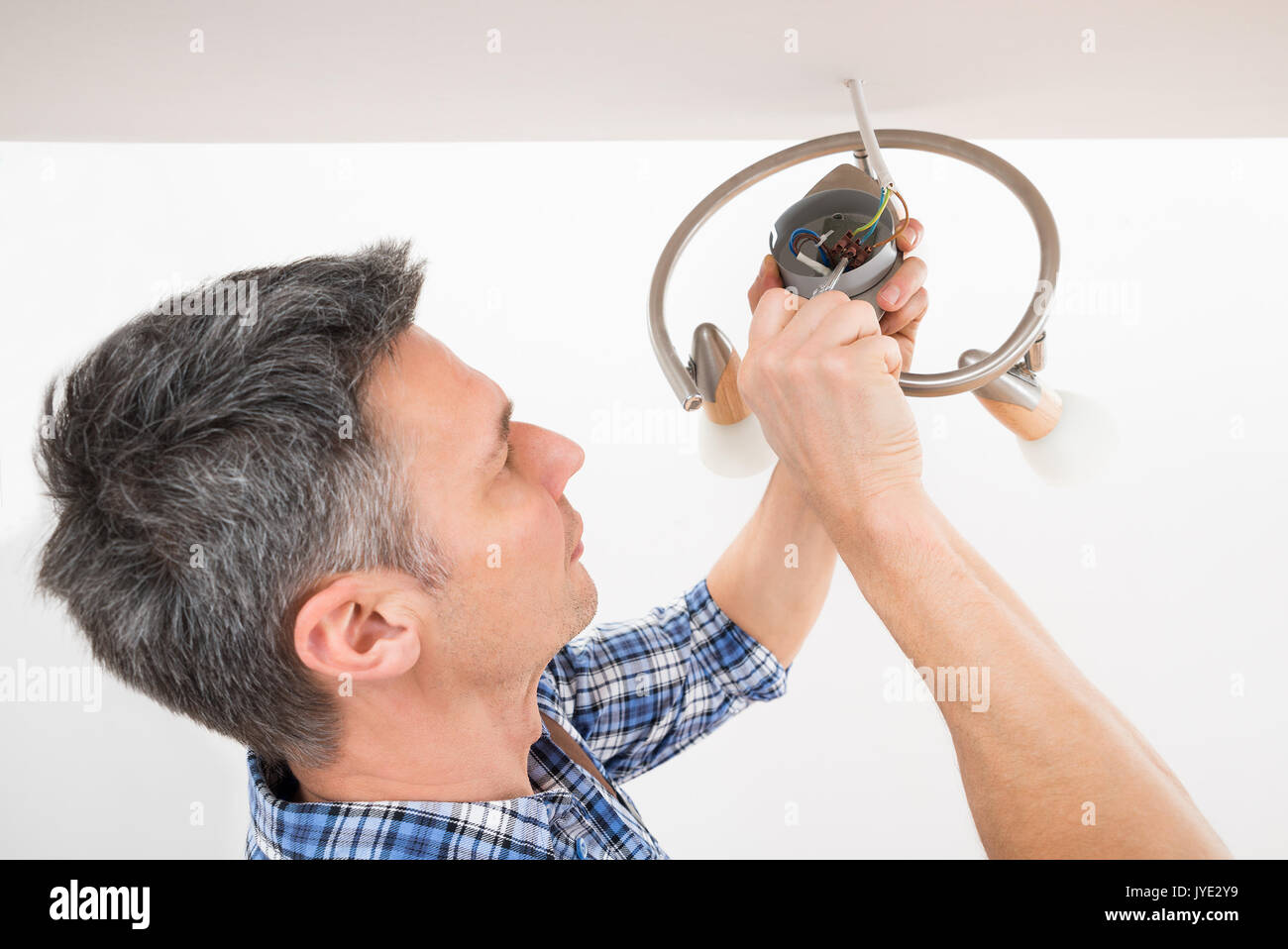 Close-up di un elettricista maschio che fissa la luce sul soffitto Foto Stock