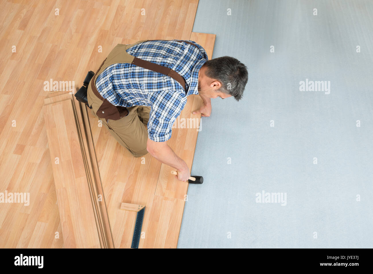 Elevato angolo di visione di un lavoratore Assemblaggio di nuovo pavimento in laminato Foto Stock