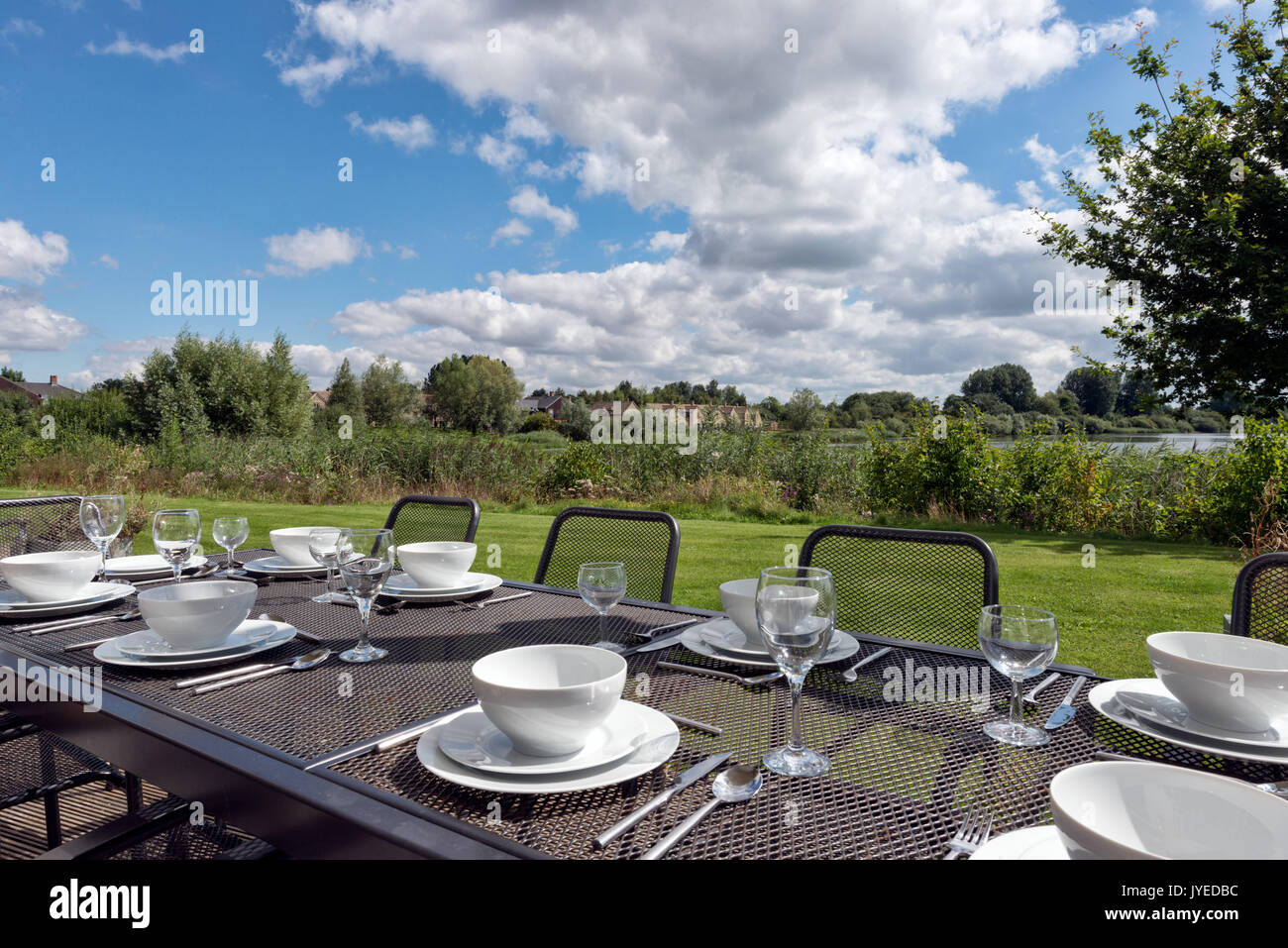Un tavolo da pranzo insieme per la cena all'aperto sotto un sole cielo estivo. Foto Stock
