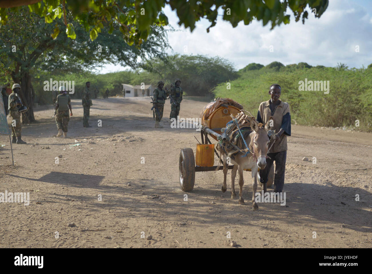 Un uomo somalo che trasportano l'acqua torna a casa sua passa l Unione Africana le truppe durante un piede in pattuglia Qoryooley, Somalia, il 29 aprile. La città di Qoryooley fu catturato a poco più di un mese fa dal al (14077925342) Foto Stock
