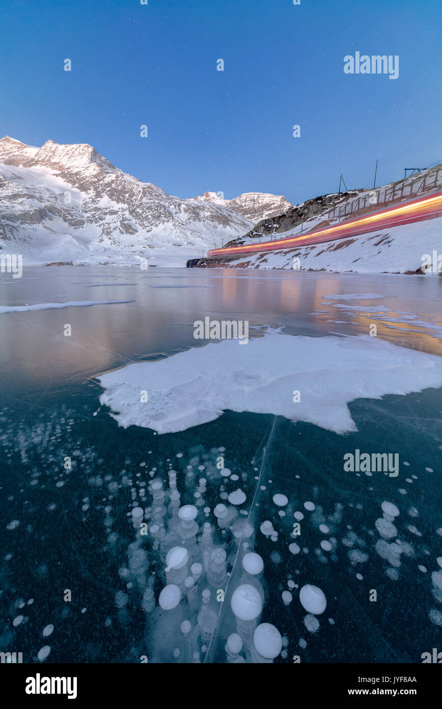 Il Bernina Express treno passa accanto al lago congelato Bianco del Bernina cantone dei Grigioni Engadina Svizzera Europa Foto Stock