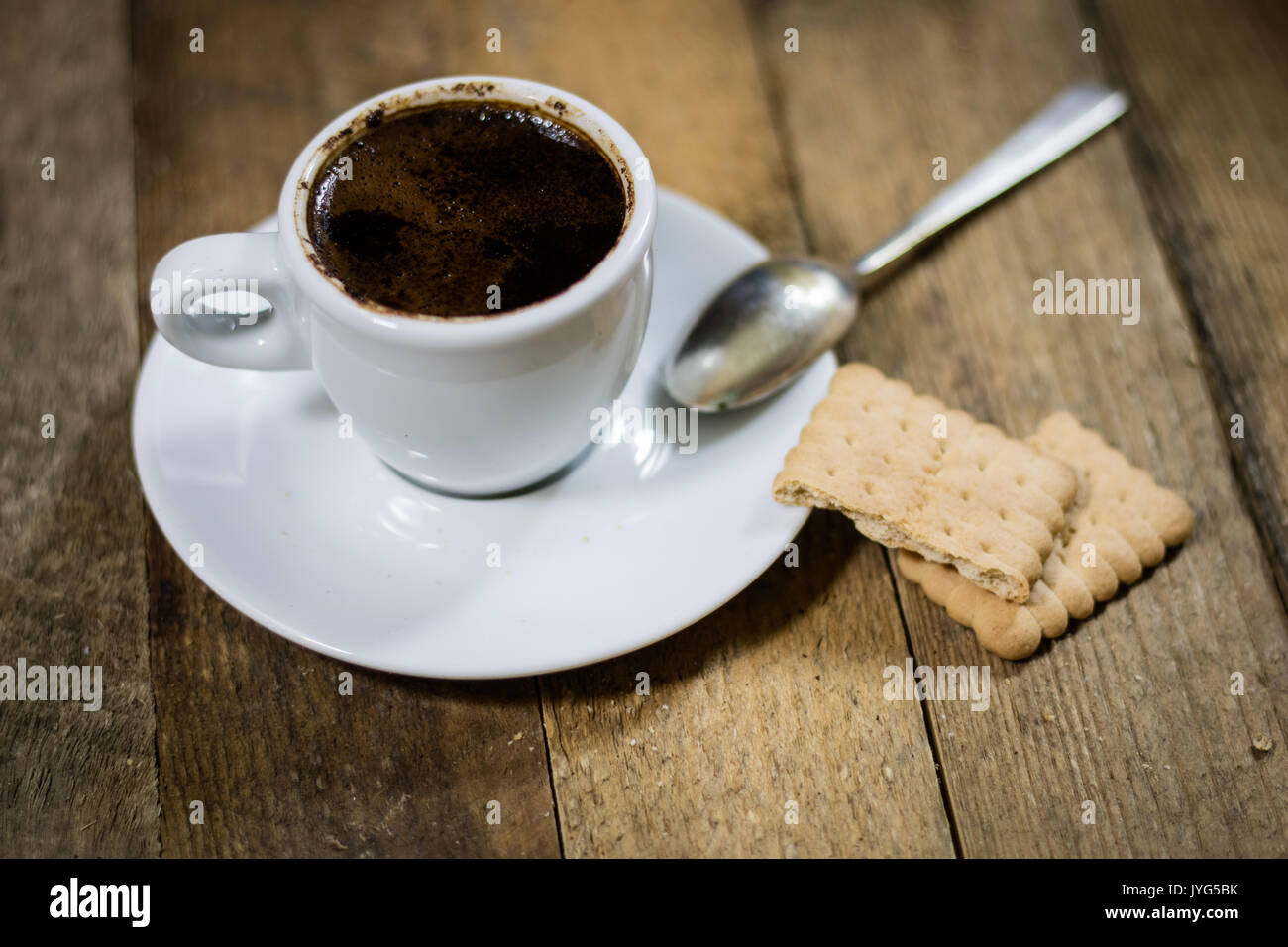Caffè in tazze su un tavolo di legno con un mulino su sfondo nero Foto Stock