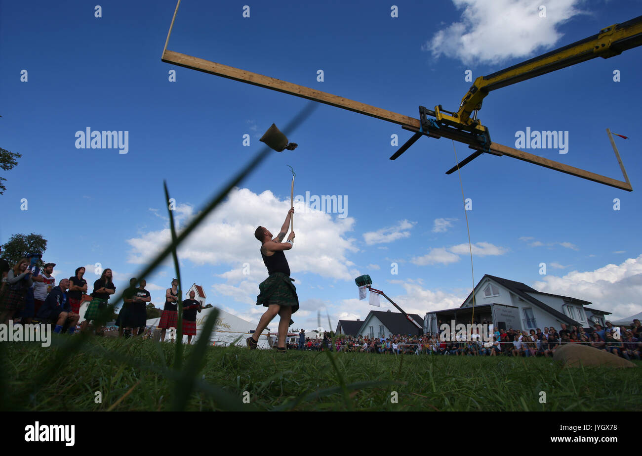 Horgenzell, Germania. 19 Ago, 2017. Un partecipante della tomaia Highlandgames sveva getta un sacco di fieno con una forcella di passo attraverso un ostacolo nella disciplina 'Sheaf Toss' in Horgenzell, Germania, 19 agosto 2017. 15 clan competere gli uni contro gli altri in varie discipline al Highlandgames. Foto: Karl-Josef Hildenbrand/dpa/Alamy Live News Foto Stock