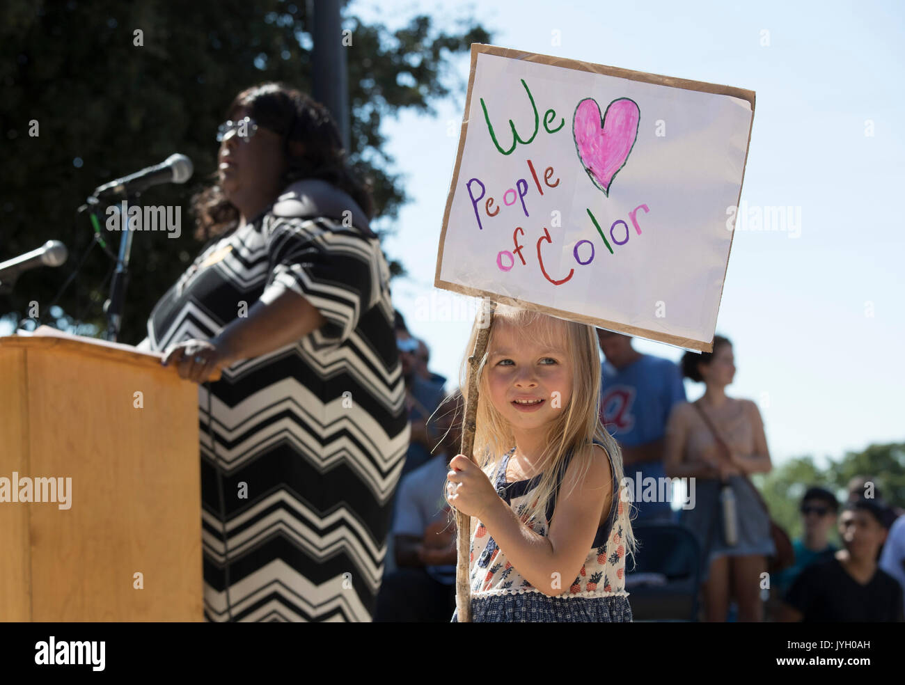 Gianna Whitehawk di Buda, TX detiene un segno come attivisti e manifestanti convergono sul Municipio per un caldo due ore di rally contro il razzismo e la presidente Donald Trump's evidenti insensibile commenti sulle recenti Charlottesville e la violenza che ha lasciato un morto. Circa mille raccolti nel mese di agosto il Texas calore. Foto Stock