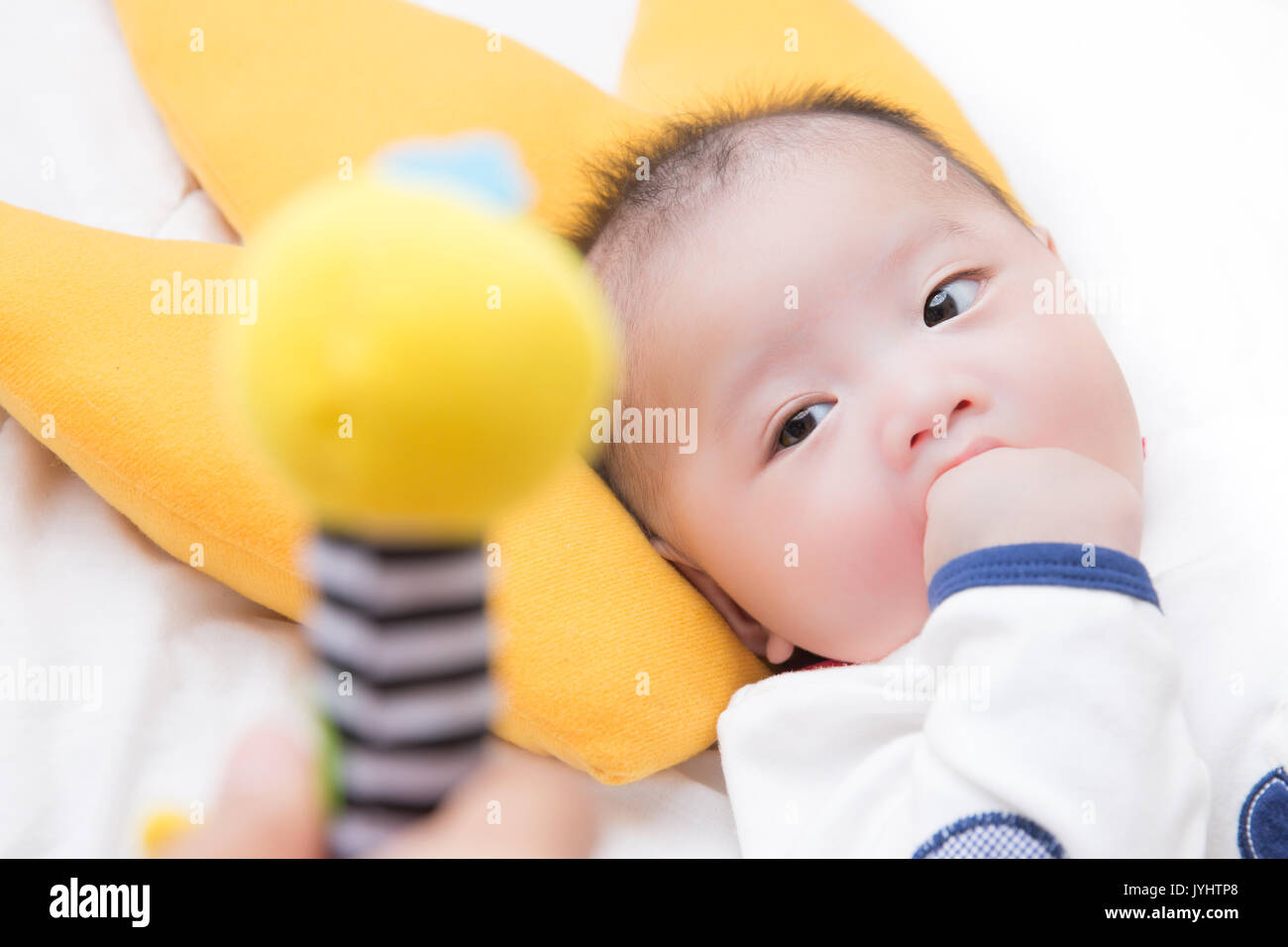 Baby boy guardando la bambola con la mano in bocca Foto Stock