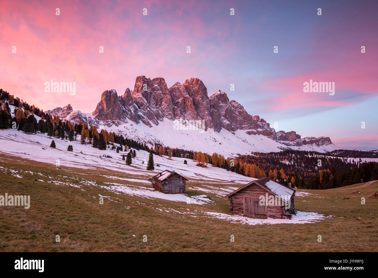 Alba con due casette in legno e Odle Dolomiti. Malga Gampen, Funes, Bolzano, Trentino Alto Adige - Sudtirol, Italia, Europa. Foto Stock