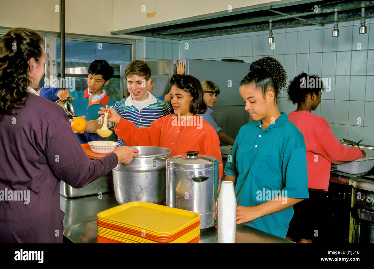 Variegata diversità etnica il gruppo giovanile che serve pasti per bambini senzatetto aiutando un altro © Myrleen Pearson Foto Stock