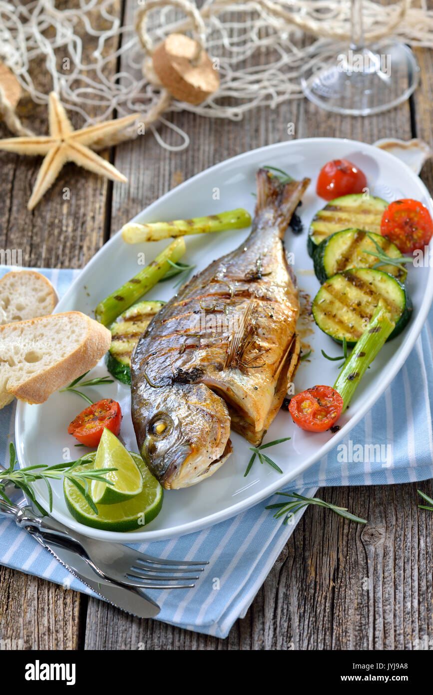 Grigliata di orata con rosmarino misto di verdure servita su un bianco  ovale piatto di pesce Foto stock - Alamy