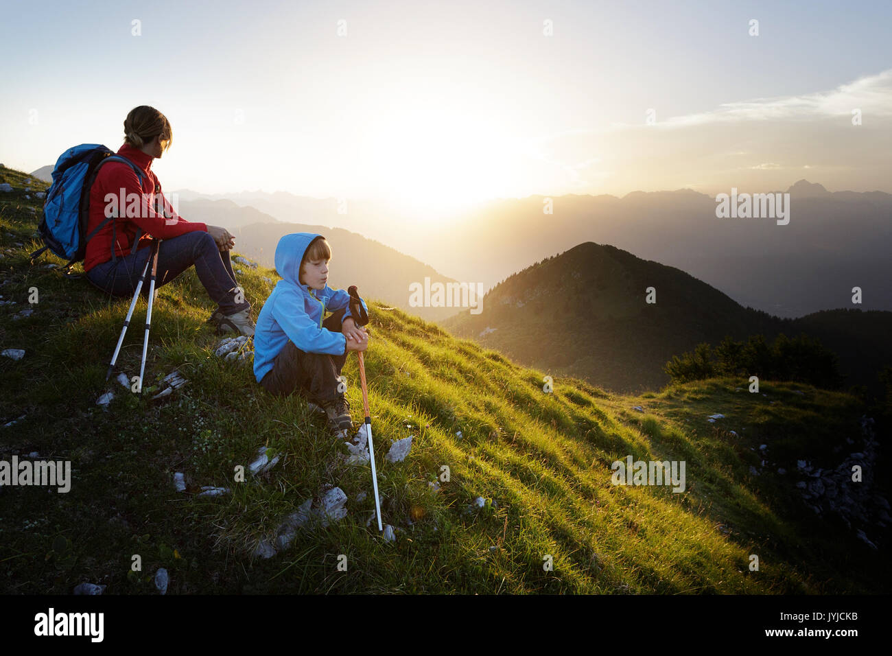 Close up di una madre e figlio seduti sulla cima di una montagna con una bella viev sul tramonto e montagne, Slatnik, Slovenia. Foto Stock