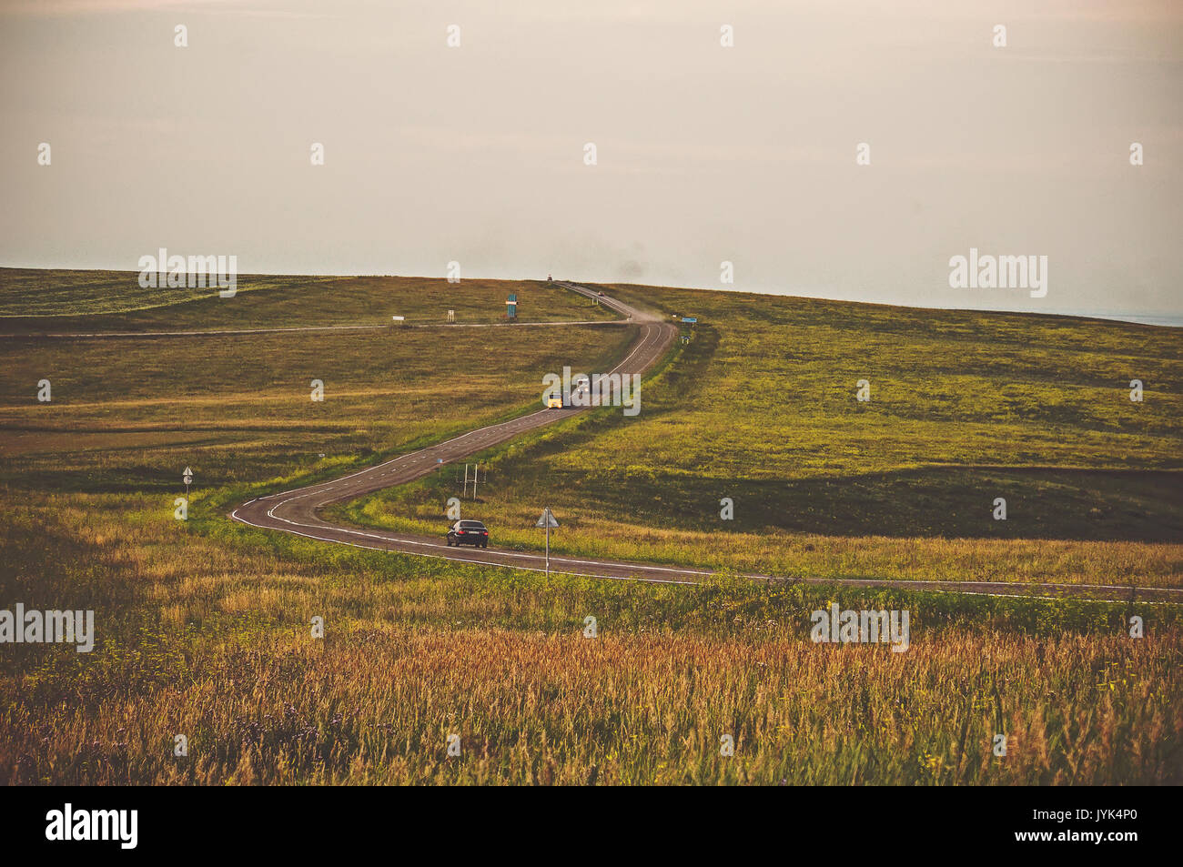 Offroad spedizione. la strada andando a distanza oltre l'orizzonte sulle colline attraverso il giallo campo di autunno Foto Stock