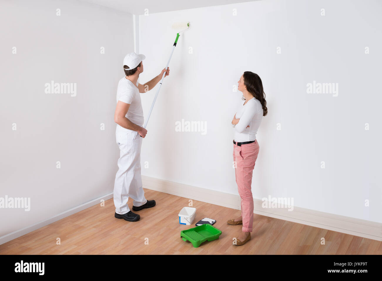 Giovani casalinga guardando al pittore muro dipinto in casa Foto Stock