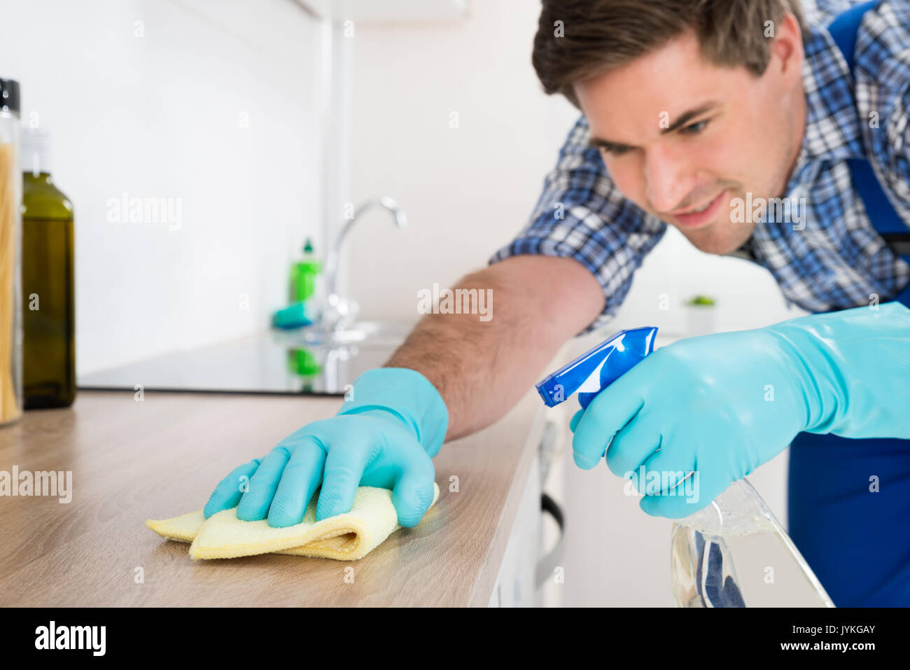 Giovane lavoratore in generale da banco di pulitura con Rag in cucina Foto Stock