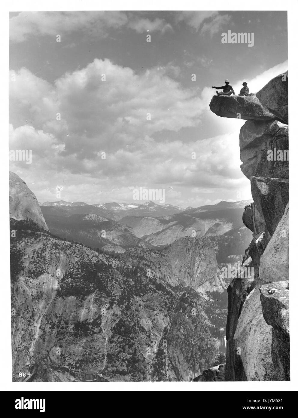 Questa fotografia del 1901 mostra A.E. McConnell e sua figlia arroccati sul bordo di Glacier Point nel Parco Nazionale di Yosemite, catturando un momento di avventura all'aperto all'inizio del XX secolo in uno dei monumenti naturali più iconici d'America. Foto Stock