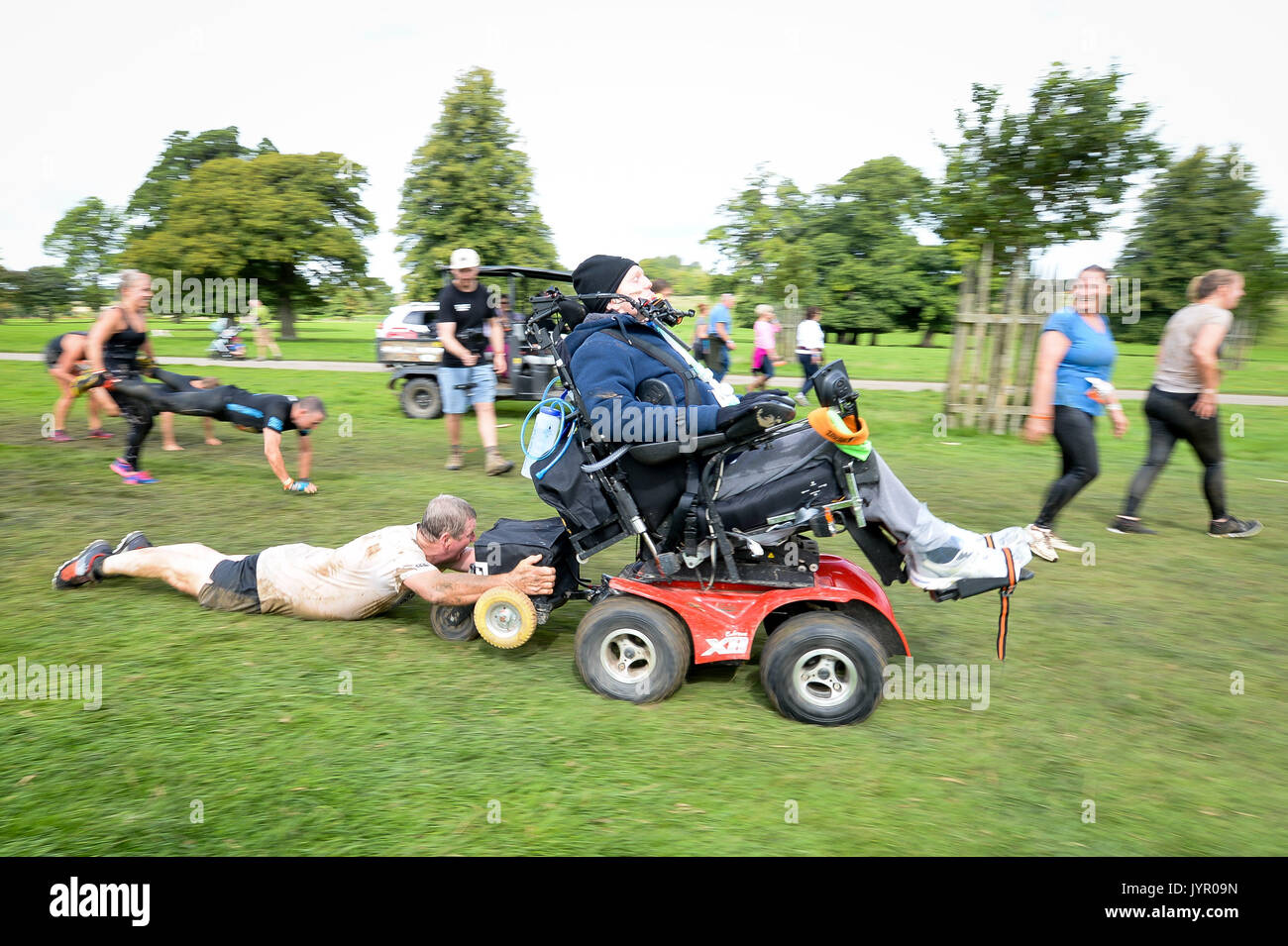 Rob Camm, che soffre da tetraplegia e paralised dal collo in giù, trascina il suo papà Ian in un 'carriola' ostacolo come egli prende parte alla sua terza dura Mudder evento al Badminton station wagon, Wiltshire, dove egli è affrontare il corso con un appositamente progettato sedia egli controlla con il suo mento. Foto Stock