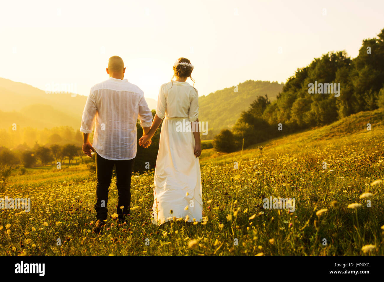 Giovane camminando sul campo con una romantica vista tramonto Foto Stock