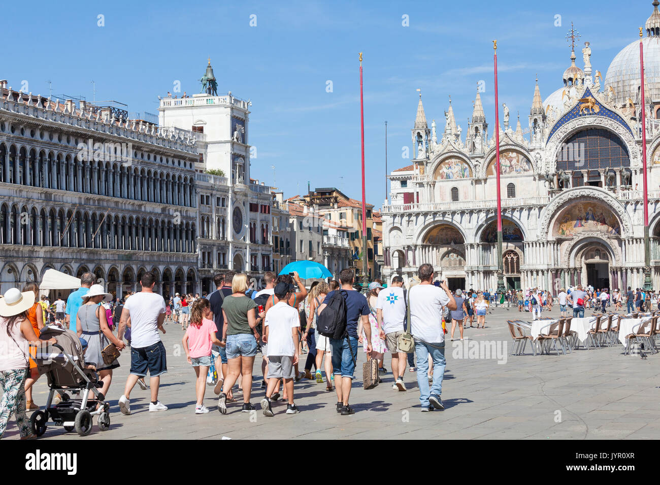Tour di gruppo con le famiglie e i bambini in Piazza San Marco, Venezia, Italia dopo il loro tour guida portante l ombrello blu a camminare verso il bas Foto Stock