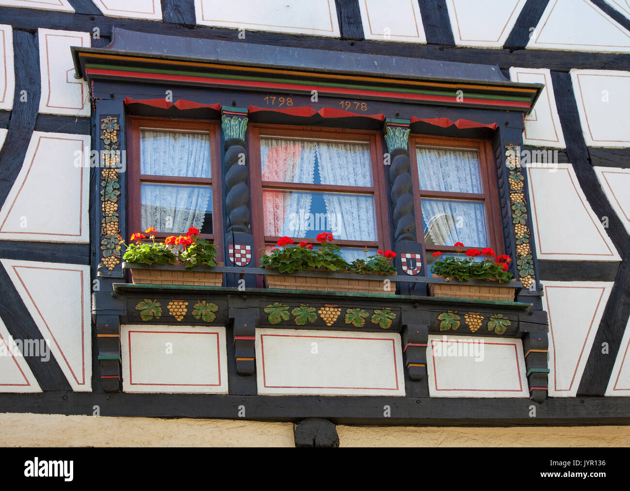 Holzschnitzerei, Weintrauben und Weinblaetter zieren einen Fensterrahmen, Fachwerkfassade im Winningen Weinort, Untermosel, Landkreis Mayen-Koblenz, R Foto Stock