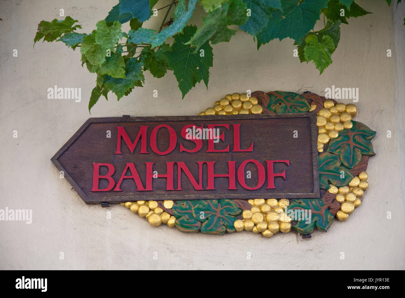 Holzschnitzerei, mit Weintrauben und Weinblaettern verzierter Wegweiser zum Mosel Bahnhof, Weinort Winningen, Untermosel, Landkreis Mayen-Koblenz, Rodano Foto Stock