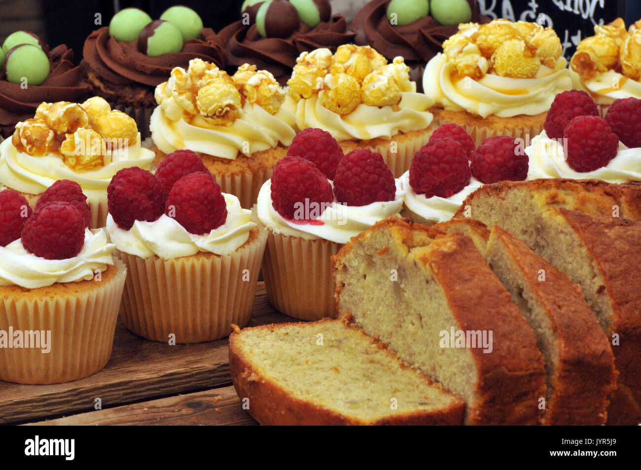 Alcune senza glutine appiccicoso e Crema ghiacciata torte di glassa sul display su un cavalletto di torta dolce zuccherino di produrre per la vendita molto tentati di dessert e dolci Foto Stock