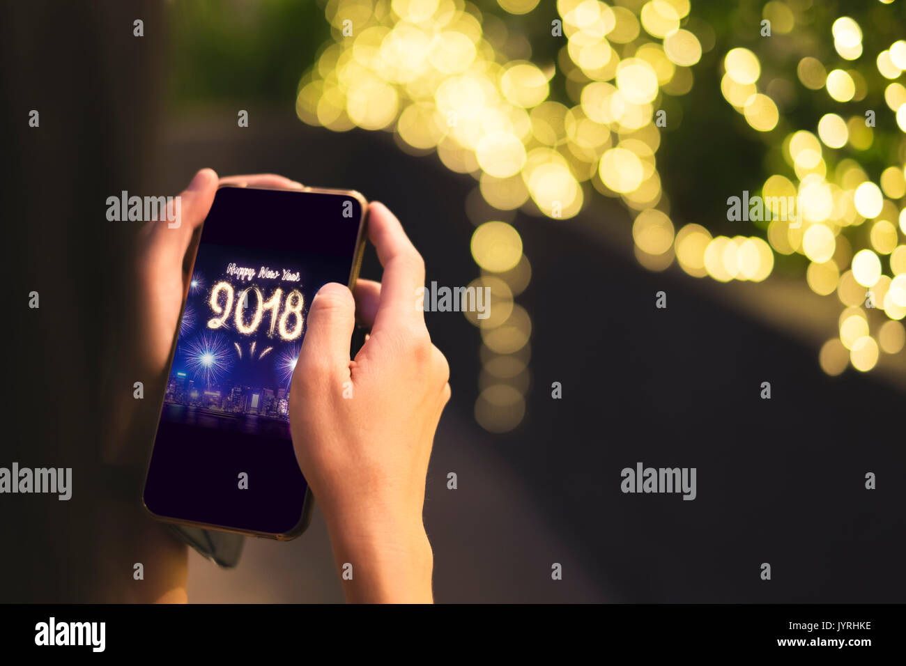 Donna mano azienda mobile con felice anno nuovo 2018 fuochi d'artificio su cityscape sullo schermo con luce sfondo bokeh di fondo,Digital greeting card vacanza. Foto Stock