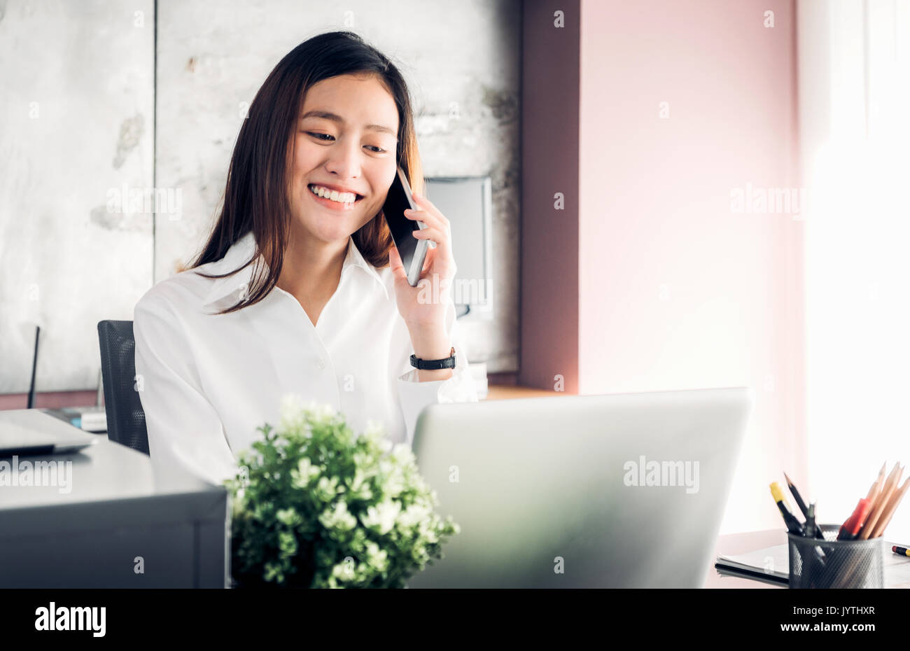 Asian imprenditrice parlando al telefono mobile nella parte anteriore del computer portatile in ufficio,Ufficio concetto di stile di vita. Foto Stock