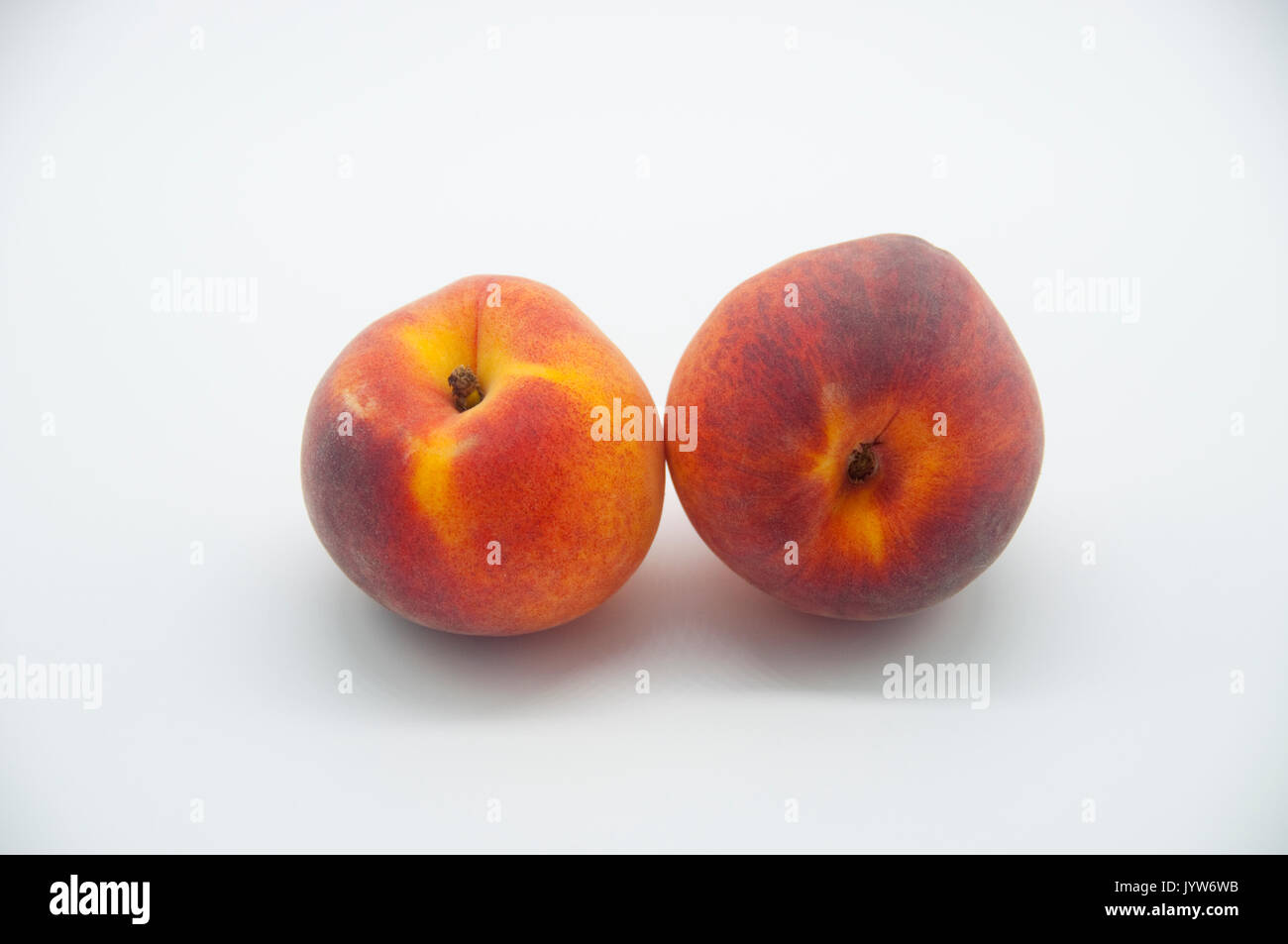 Due pesche mature, fotografato su uno sfondo bianco. Foto Stock