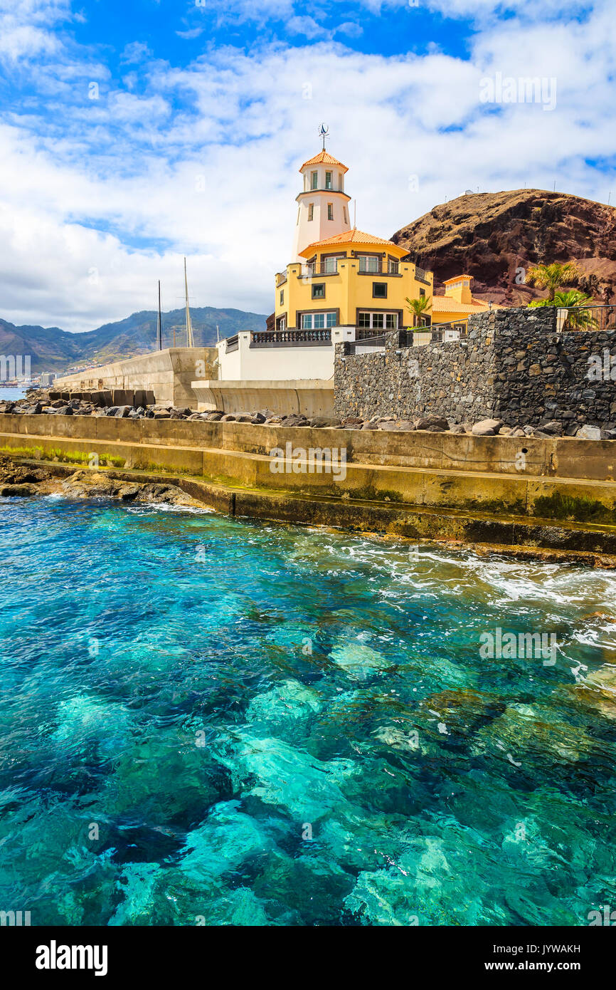 Oceano verde smeraldo di acqua e edificio del faro sulla costa dell'isola di Madeira, Portogallo Foto Stock