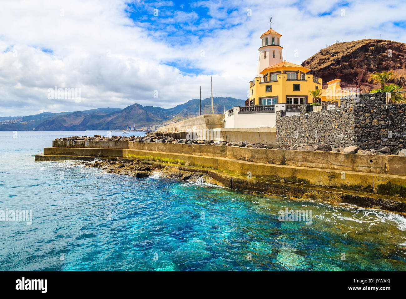 Oceano verde smeraldo di acqua e edificio del faro sulla costa dell'isola di Madeira, Portogallo Foto Stock