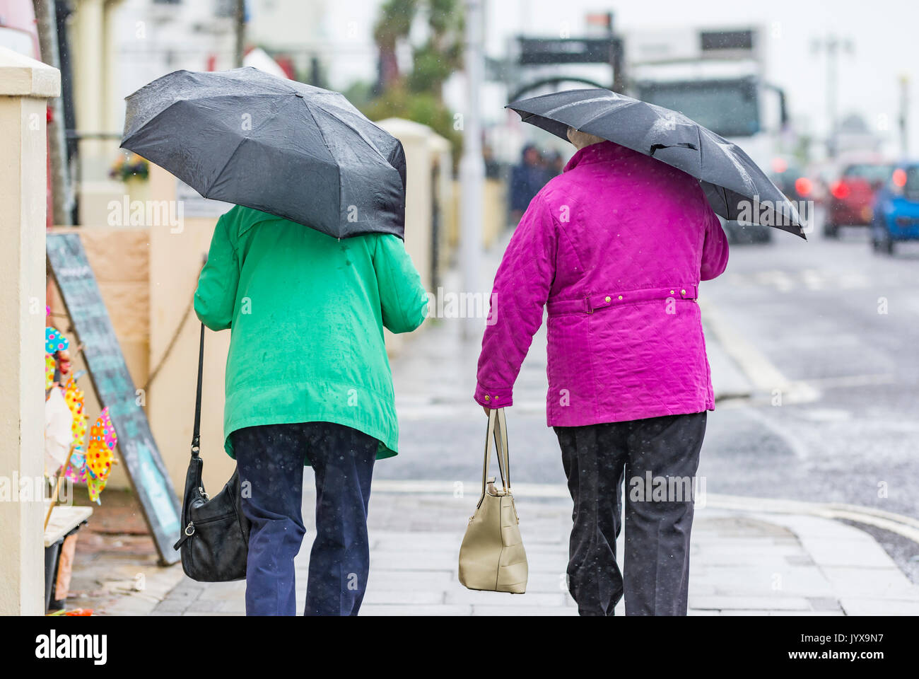Vista posteriore di persone a piedi sotto la pioggia ombrelli azienda. Foto Stock