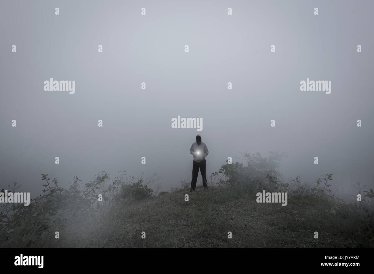 L'uomo minaccioso In Hoodie nella nebbia Shing luce Foto Stock